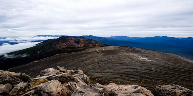 A rocky landscape with mountains in the background

Description automatically generated
