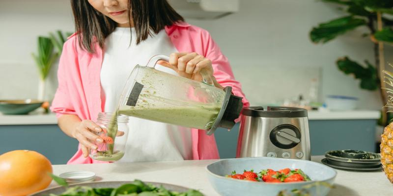 A child pouring green liquid into a blender

Description automatically generated